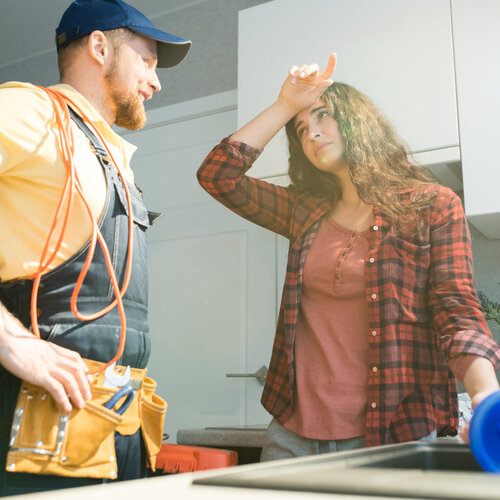 plumber helping a young woman with a clogged drain