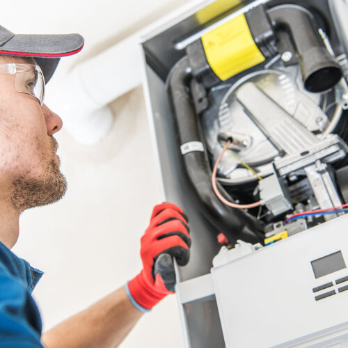 technician replacing parts in a heating system