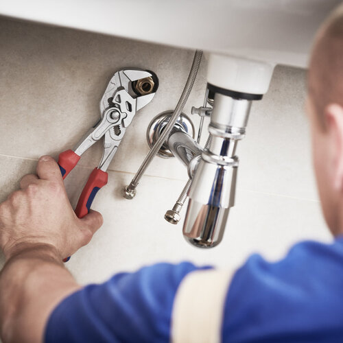 plumbing contractor performing repairs under a sink