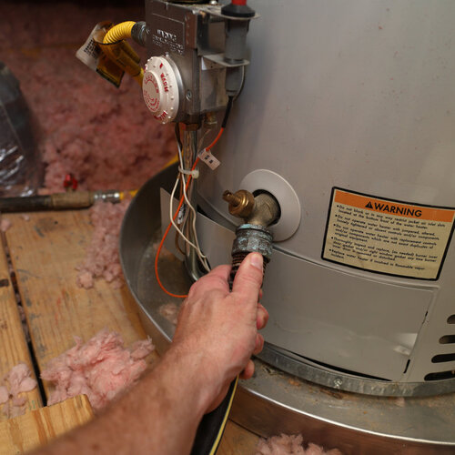 plumber inspecting a hot water heater hose