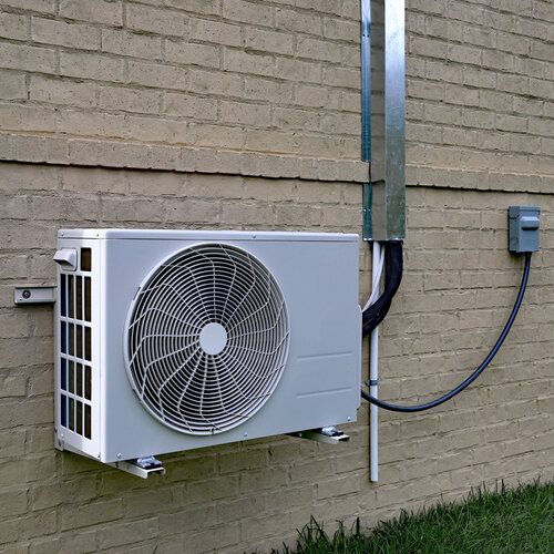 mini-split AC system against a brick wall