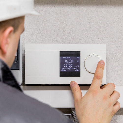 technician adjusting an HVAC thermostat